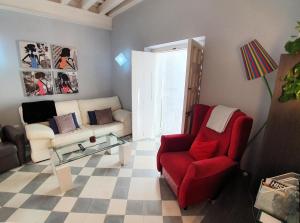 a living room with a red chair and a couch at APARTAMENTO APODACA in Cádiz