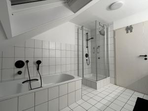 bagno bianco con vasca e doccia di Ferienwohnung Mooi a Kraichtal
