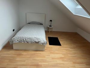 una camera bianca con letto e pavimento in legno di Ferienwohnung Mooi a Kraichtal