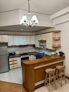 a kitchen with white cabinets and a counter with two stools at Riverview Home @Waterfront KCH in Kuching