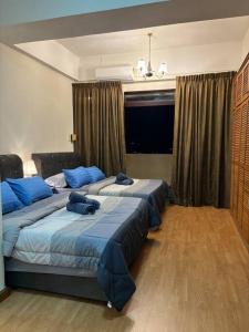 a bedroom with two beds with blue pillows at Riverview Home @Waterfront KCH in Kuching