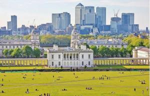 a large building with people in a field in front of a city at Cosy 1Bedroom Apartment in Greenwich Cutty Sark in London