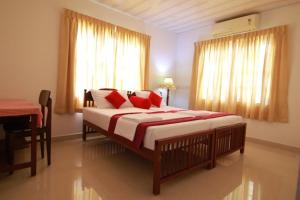 a bedroom with a bed with red pillows and a window at Beena Homestay in Fort Kochi