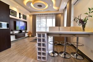 a living room with a bar with chairs and a television at ENTEBBE-STAY Aparthotel - KITOORO in Entebbe
