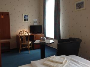 オストゼーバート・ニーンハーゲンにあるHotel Nienhäger Strandのベッド、テーブル、テレビが備わるホテルルームです。