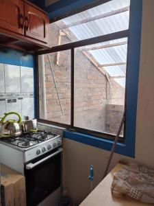 une cuisine avec une cuisinière et une fenêtre dans l'établissement HUANCAYO DPTO ACOJEDOR, à Huancayo