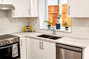 a kitchen with white cabinets and a sink at ENTIRE Garden Apt-Private Parking+Central Location in Vancouver