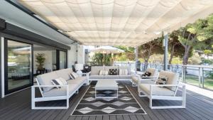 a porch with white chairs and an umbrella at Villa Dune, Luxury Villa, 5 min walk to the beach in Marbella