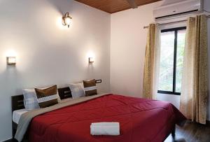 a bedroom with a red bed with a window at Marari Charlys Homestay in Mararikulam