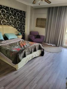 ein Schlafzimmer mit einem Bett und einem lila Stuhl in der Unterkunft دوبلكس فى السياحية السادسة in Madinat as-Sadis min Uktubar + 16 Fotos