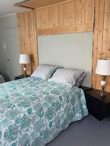 a bedroom with a large bed with two lamps at Chalet Pakingan in Cap-Chat