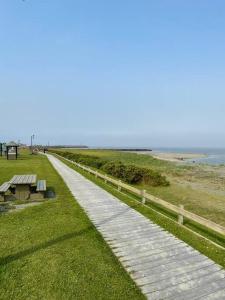 a walkway next to the beach with a picnic table at Chalet Pakingan in Cap-Chat