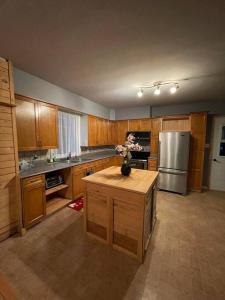 eine Küche mit Holzschränken und einem Kühlschrank aus Edelstahl in der Unterkunft Chalet Pakingan in Cap-Chat