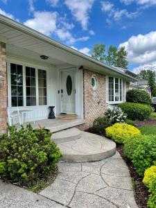 uma casa de tijolos com uma porta branca e um alpendre em Gorgeous Williamsville Home in Central Location em Buffalo
