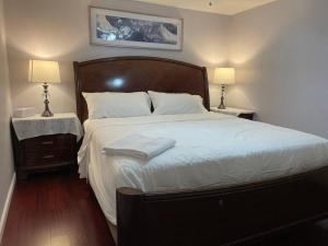 a bedroom with a large bed with white sheets and two lamps at Gorgeous Williamsville Home in Central Location in Buffalo