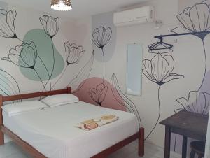 a bedroom with a bed with flowers on the wall at Jambudvipa Hostel in Natal