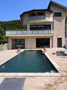 two people sitting in a swimming pool in front of a house at Villa Majetic na Uni in Bihać