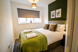 um quarto com uma cama com paredes verdes e uma janela em Woodcock House 3 Bedrooms Workstays UK em Lackenby