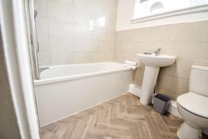 a bathroom with a sink and a tub and a toilet at Woodcock House 3 Bedrooms Workstays UK in Lackenby