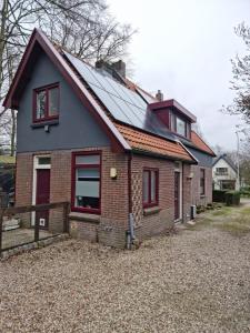 ein kleines Backsteinhaus mit einem roten in der Unterkunft Logeren bij Sabine en JW in Beekbergen