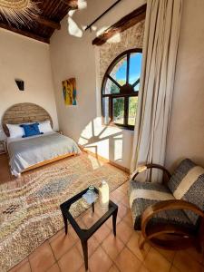 Schlafzimmer mit einem Bett, einem Tisch und einem Fenster in der Unterkunft Maison La Chèvre in Essaouira