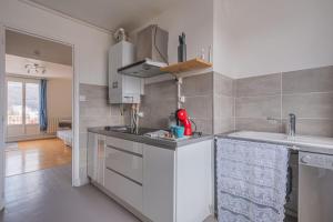 uma cozinha com armários brancos e um lavatório em Le cocon em Fontaine