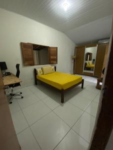 a bedroom with a yellow bed and a desk at Agradável Casa de praia no Francês in Marechal Deodoro
