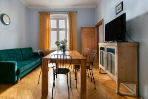 ein Wohnzimmer mit einem Tisch und einem grünen Sofa in der Unterkunft Cozy Apartments Krakowska Street, Kazimierz District in Krakau