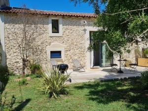 a stone house with chairs and a grill in front of it at Le Mas du Castellas 5* in Le Thor