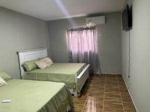 een kleine kamer met 2 bedden en een televisie bij Aparta Hotel Esa Buya in San Fernando de Monte Cristi