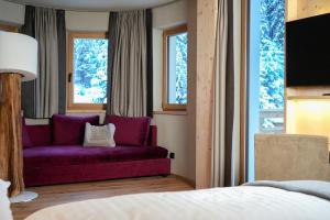 a bedroom with a purple couch in front of a window at Hotel Pozzamanigoni in Selva di Val Gardena