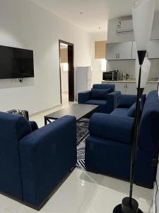 sala de estar con sofás azules y TV en مشتى الجنوب ( دخول ذكي ) en Salhabah