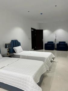- 2 lits dans une chambre avec des chaises bleues dans l'établissement مشتى الجنوب ( دخول ذكي ), à Salhabah