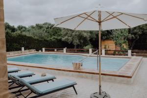 uma piscina com duas cadeiras e um guarda-sol ao lado em Finca S'Agret em Capdepera