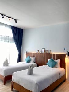 two beds in a hotel room with blue curtains at Blue Ba You Resort in Ban Khlong Haeng