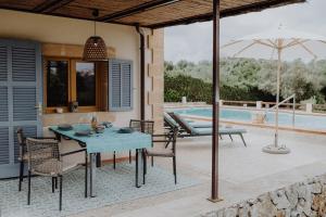 a patio with a table and chairs and an umbrella at Finca S'Agret in Capdepera