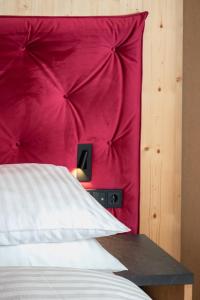 a bed with a red headboard with a red wall at Hotel Pozzamanigoni in Selva di Val Gardena