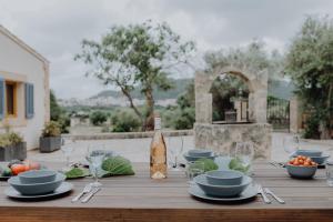 a wooden table with a bottle of wine and glasses at Finca S'Agret in Capdepera