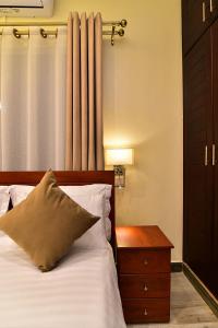 a bedroom with a bed with a nightstand and a window at ENTEBBE STAY Apart-Hotel in Entebbe