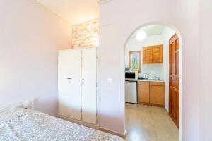 a white room with a bed and a kitchen at natura studios almyros in Almiros Beach