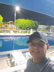 a man wearing a hat sitting next to a pool at Paulo Afonso BA Capitalbda Energia e do turismo in Paulo Afonso