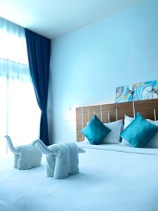 um quarto com uma cama branca e almofadas azuis em Blue Ba You Resort em Ban Khlong Haeng