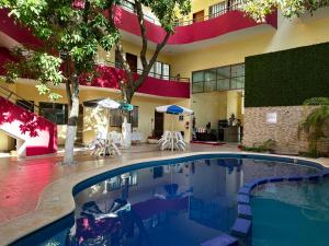 a pool in a hotel with chairs and a building at Hotel San Miguel Playa del Carmen in Playa del Carmen
