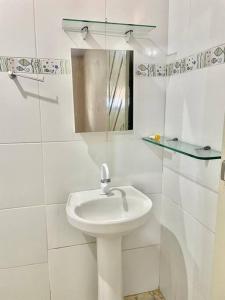 a white bathroom with a sink and a mirror at Paz, arte, beleza e natureza na praia de Sagi in Baía Formosa