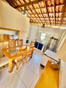 a dining room with a table and chairs and a kitchen at Paz, arte, beleza e natureza na praia de Sagi in Baía Formosa