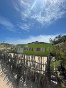 a fence in front of a green building on a beach at Paz, arte, beleza e natureza na praia de Sagi in Baía Formosa