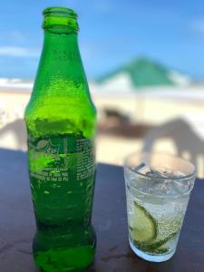una botella verde y un vaso de agua con lima en Paz, arte, beleza e natureza na praia de Sagi, en Baía Formosa