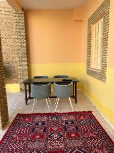 a dining room with a table and chairs and a rug at Dar Medina Tozeur in Tozeur