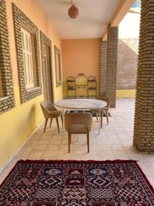 a patio with a table and chairs and a rug at Dar Medina Tozeur in Tozeur
