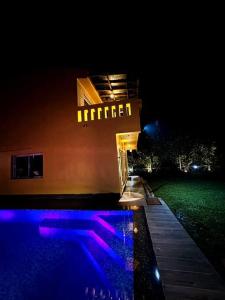 a hotel at night with a pool in front of it at The Orchard House in Raichak